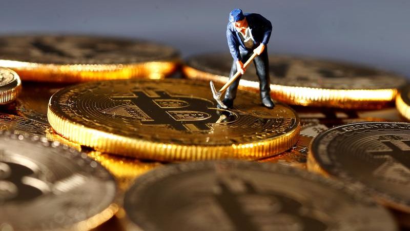 A small toy figure is seen on representations of the Bitcoin virtual currency